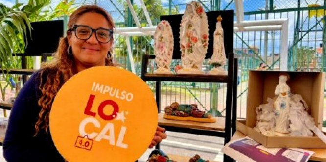 Mujer emprendedora sonriendo con un aviso en la mano que tiene el logo de Impulso Local 4.0